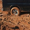 The rear whell of a car stuck in the mud.